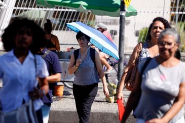Tânia Rêgo/Agência Brasil Rio de Janeiro (RJ), 17/02/2024 -Transeuntes se protegem do forte calor nas ruas do centro da cidade. Cidade do Rio de Janeiro atinge nível 4 de calor. Marco é caracterizado por temperaturas que podem chegar a 44ºC Foto: Tânia Rêgo/Agência Brasil
